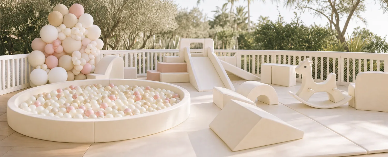 A full soft play setup on a sunlit terrace — ball pit, slide, foam shapes and a rocking horse